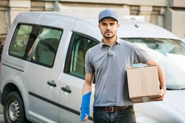 Senin nakliye işte. arabasını, önünde sokakta onun karton kutu ile kap ayakta ile gri tişörtlü teslimat adam kameraya gülümseyen