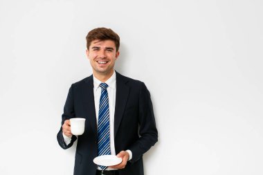 takım elbiseli, beyaz arka plan üzerinde bir kahve içme, zor bir gece sonra kurtarma veya yeni bir gün başlatma office işadamı, şık erkek gülümseyen