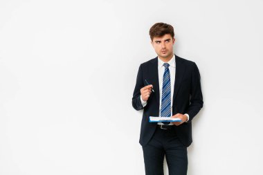 Beyaz arka plan üzerinde duran ve Pano elinde bir çözüm hakkında düşünme elbiseli şık adam