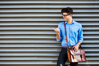 yakışıklı office adam gözlük ve deri çanta, bir duvara karşı ayakta ve çevresindeki boş alan tarafında sunma