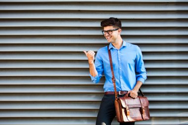 yakışıklı office adam gözlük ve deri çanta, bir duvara karşı ayakta ve çevresindeki boş alan tarafında sunma