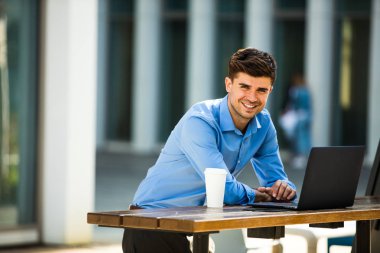 kendinden emin antrepreneur kamera, uzaktan ile laptop önünde dışında çalışma ve bir fincan kahve için gülümseyen