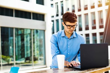 Genç office adam odaklı çalışma üzerinden dışında-laptop yanında, kahve ile uzaktan çalışma