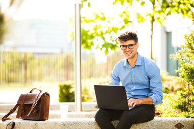 Uzaktan çalışma. Genç yakışıklı antrepreneur çalışmaktan dışında dizüstü bilgisayar önünde ile güneşli güzel gününde