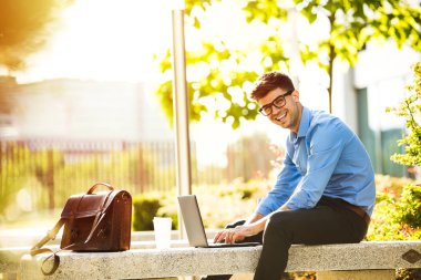 Uzaktan çalışma. Genç yakışıklı antrepreneur çalışmaktan dışında dizüstü bilgisayar önünde ile güneşli güzel gününde