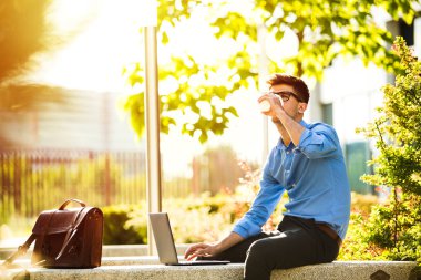 Uzaktan çalışma. Genç yakışıklı antrepreneur çalışmaktan dışında dizüstü bilgisayar önünde ile güneşli güzel gününde