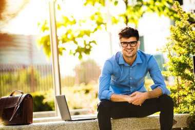 Uzaktan çalışma. Genç yakışıklı antrepreneur çalışmaktan dışında dizüstü bilgisayar önünde ile güneşli güzel gününde