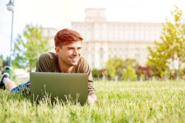 otların arasında yalan arıyorsunuz veya dizüstü bilgisayar, dışarıda park bir şehir merkezinde çalışan yakışıklı genç adam, öğrenci,