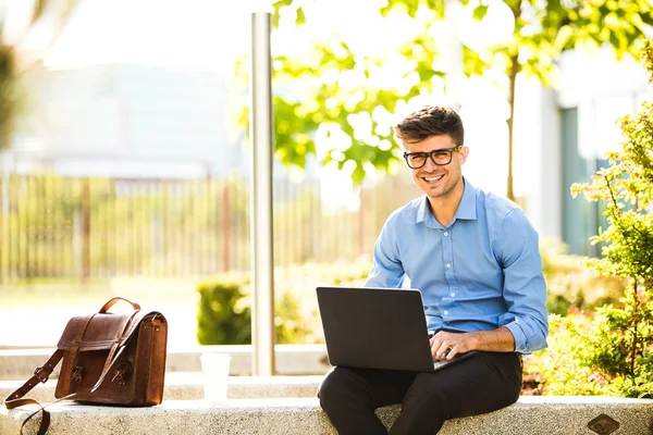Uzaktan çalışma. Genç yakışıklı antrepreneur çalışmaktan dışında dizüstü bilgisayar önünde ile güneşli güzel gününde