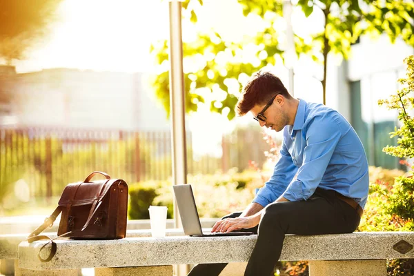 remote working. young handsome antrepreneur working from outside, in sunny beautiful day, with laptop in front