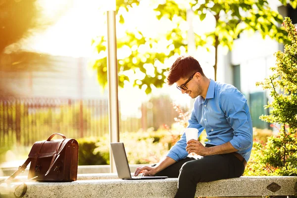 remote working. young handsome antrepreneur working from outside, in sunny beautiful day, with laptop in front