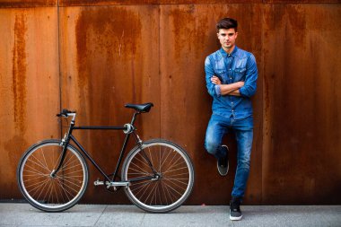 şehrin hızlı. kot kıyafeti yanında onun tek hız bisiklet paslı bir arka plan üzerinde şık bir adamla bir şehirde güzel bir ulaşım kavramı