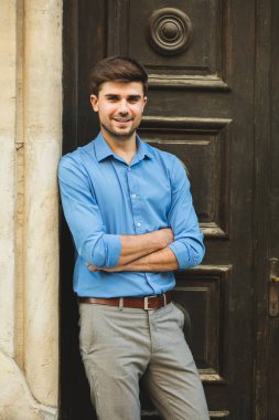 Konuklar veya istemciler için bekliyor. olumlu tutum ve katlanmış silah ile içinbeklediğini eski bir ahşap kapı önünde ayakta zarif adam