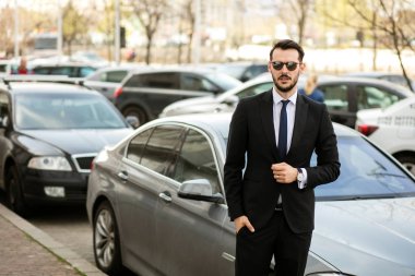 başarılı şık erkek güneş gözlüğü ve şık takım elbise onun limuzin önünde duran ve güven ile seyir