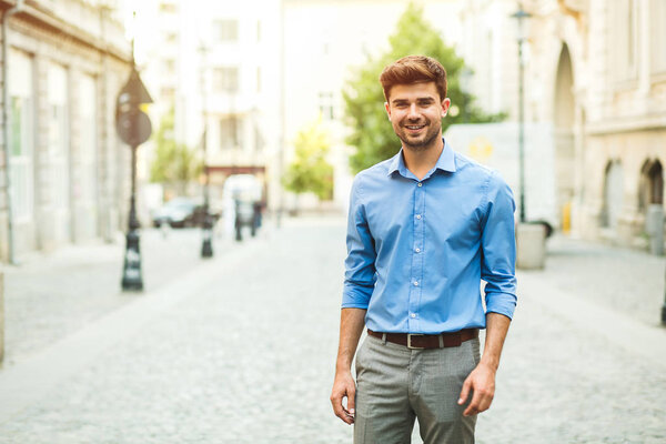 going to office. young handsome and confident guy in smart casual outfit, office day, walking outside on the street and looking to camera