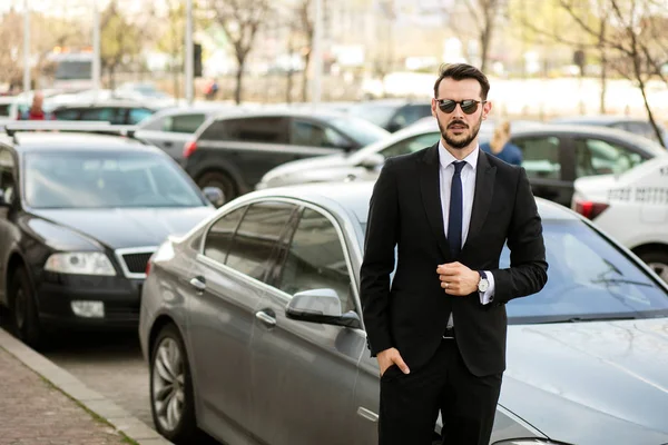 başarılı şık erkek güneş gözlüğü ve şık takım elbise onun limuzin önünde duran ve güven ile seyir