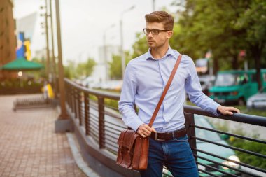 office sonra eve gidiyorum. yakışıklı zeki casual adam gözlük ve deri çanta dışında işten sonra yürüyüş