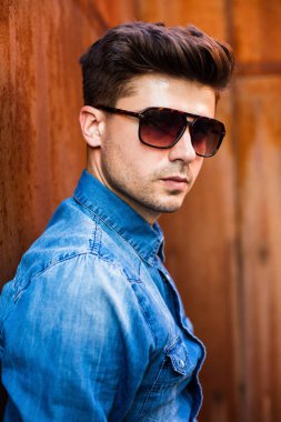 kendine güvenen bakan seksi birisi paslı bir arka plan üzerinde suglasses ve kot gömlek ile portre kadar kapatın