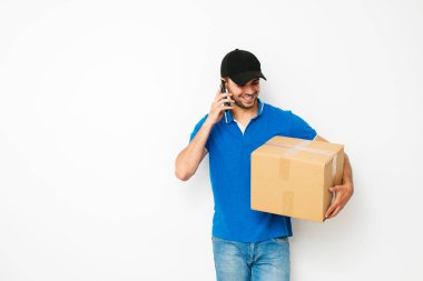 hızlı teslimat. teslimatçı mavi gömlekli cardbox taşıyan ve paket, beyaz arka plan üzerinde sahibine başvurun için cep telefonunu kullanma