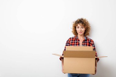 Bazı mooving kutularını boş duvar üzerinde kareli gömlek duran genç yorgun kıvırcık kadın