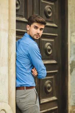 Konuklar veya istemciler için bekliyor. zarif adam sabırla bekleyen biri için eski bir ahşap kapı önünde ayakta