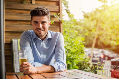 İşten sonra rahatla. Ofis iş sonra bir bira dışında ile terrace adlı genç adam, rahatlatıcı akıllı