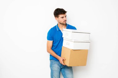 Genç adam elinde, cardbox sahip yeni bir yerde kişisel eşyalarını hareketli mavi gömlekli tarafına bakarak beyaz izole