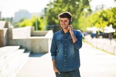 cep telefonu dışında sokakta konuşurken kot kıyafeti genç öğrenci