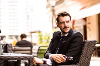 Ön kamera, güven ile bazı eski şehrin güzel terasta oturup kahvaltı iş adamı arıyor dizüstü bilgisayar ile yakışıklı başarılı adam portresi