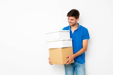 Yeni yer Merhaba de. mavi t-shirt mooving genç adam eşyalarını cardboxes sevinç, yeni yeri içinde izole beyaz