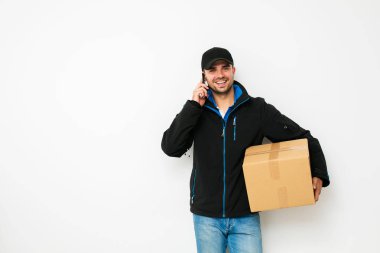 Senin nakliye işte. Onun cardbox ile cep telefonu, beyaz arka plan üzerinde konuşurken teslimatçı