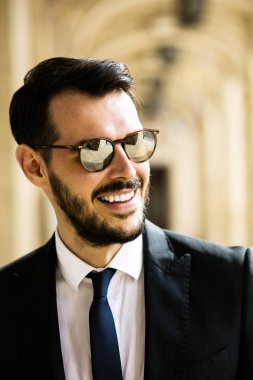 şık şık adam, ayakta dışında güneş gözlüğü ile büyük bir salonda ve güçlü seyir başarılı işadamı portresi