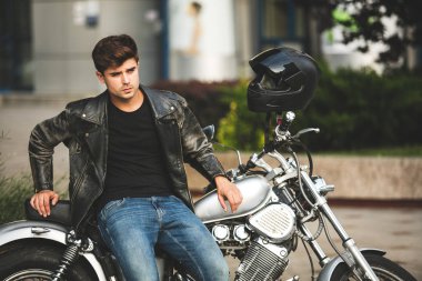 Genç ve güzel. yakışıklı ve rahatlatıcı bir adam motorsikletiyle içinbeklediğini şehir merkezinde oturan