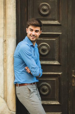 Konuklar veya istemciler için bekliyor. olumlu tutum ve katlanmış silah ile içinbeklediğini eski bir ahşap kapı önünde ayakta zarif adam