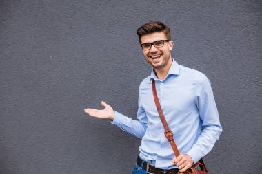 Boş tarafı işaret. yakışıklı zeki casual adam gözlük ve güven ve gülümseme ile boş bir alan onun yanında işaret dışında deri çanta