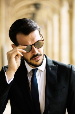 şık şık adam, ayakta dışında güneş gözlüğü ile büyük bir salonda ve güçlü seyir başarılı işadamı portresi