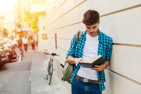 Красивый Молодой Человек Студент Рюкзаком Стоящий Снаружи Стены Читающий Книгу — стоковое фото