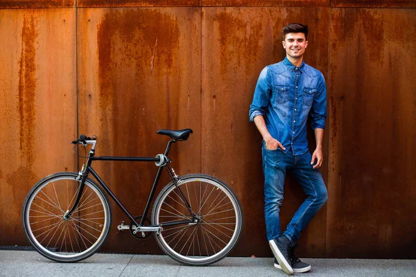 şehrin hızlı. kot kıyafeti yanında onun tek hız bisiklet paslı bir arka plan üzerinde şık bir adamla bir şehirde güzel bir ulaşım kavramı