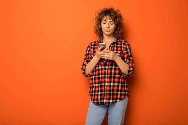 Mooie Gekrulde Vrouw Een Geruite Shirt Spijkerbroek Permanent Een Oranje — Stockfoto