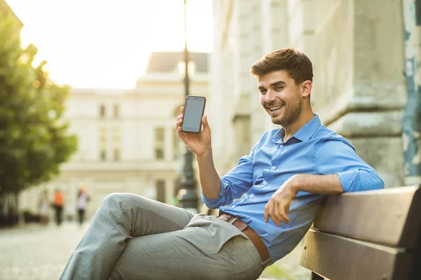 elegant man presenting his cellphone, or aplication, to camera with smile and confidence