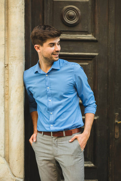 waiting for the guests or clients. elegant man standing in front of an old wooden door waiting for someone