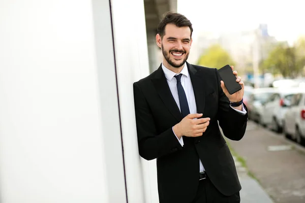 Przystojny Mężczyzna Elegancki Suitsmiling Aparatu Pokazuje Swój Telefon Komórkowy Poza — Zdjęcie stockowe