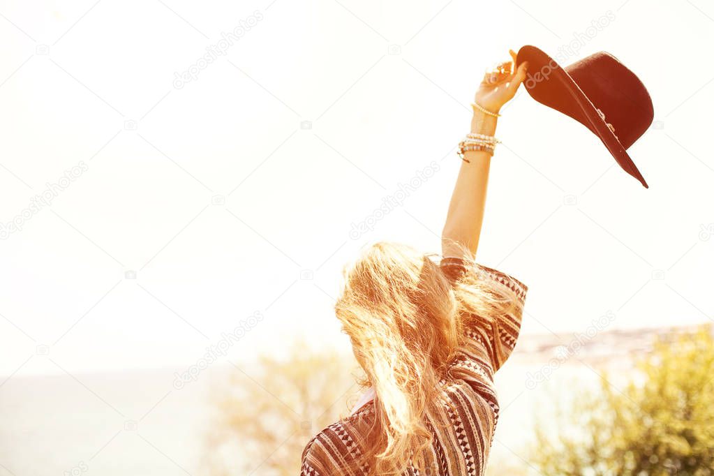 young beautifull and free girl with black hat traveling and enjoying freedom and youth, waving the hat in the air