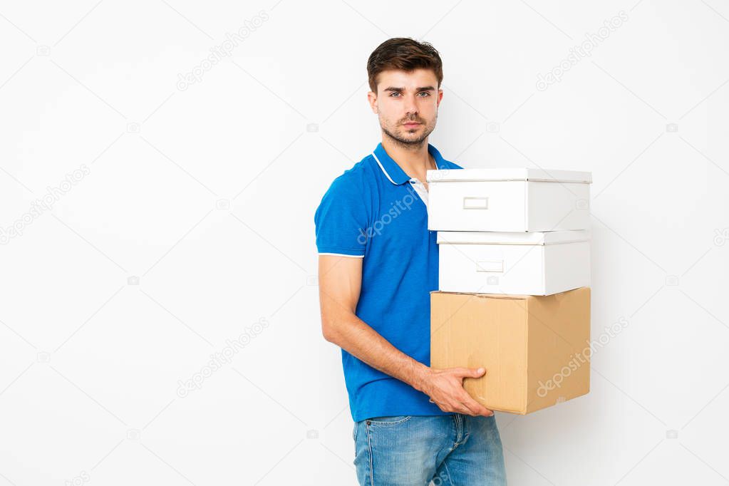 young man in blue shirt moving his personal stuff in a new place, having cardbox in hands, isolated on white looking to camera