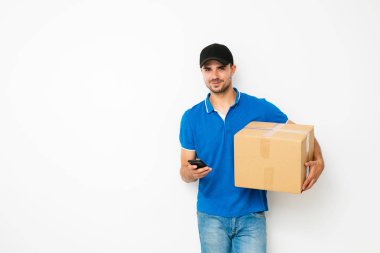 hızlı teslimat. teslimatçı mavi gömlekli cardbox taşıyan ve paket, beyaz arka plan üzerinde sahibine başvurun için cep telefonunu kullanma
