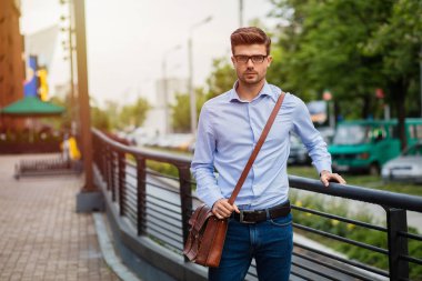 office sonra eve gidiyorum. yakışıklı zeki casual adam gözlük ve deri çanta dışında işten sonra yürüyüş