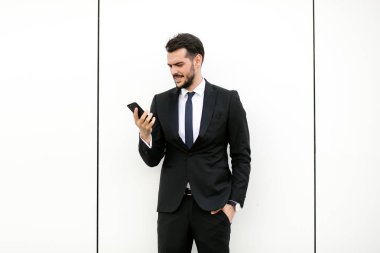 cep telefonunu kullanarak ve gülümseyen, reciving iyi haberler takım elbiseli şık yakışıklı