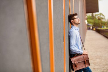 zor bir gün. yakışıklı akıllı casual adam gözlük ve mavi gömlek, dışında yorgun ve üzgün gri bir duvara dinlenme
