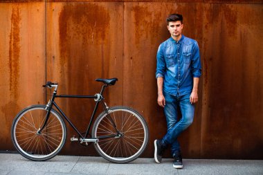 şehrin hızlı. kot kıyafeti yanında onun tek hız bisiklet paslı bir arka plan üzerinde şık bir adamla bir şehirde güzel bir ulaşım kavramı