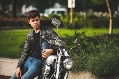 Genç ve güzel. yakışıklı ve rahatlatıcı bir adam motorsikletiyle içinbeklediğini şehir merkezinde oturan